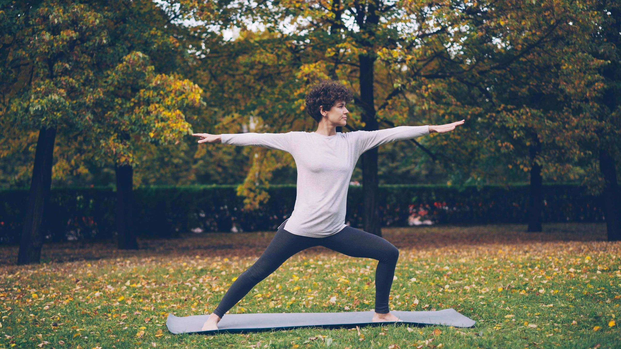 Yoga warrior pose in autumn park